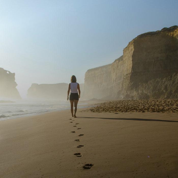 Woman walking on beach next to ocean after taking Kanin energy drink for immune support and energy