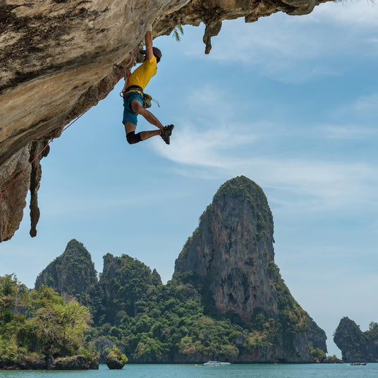 Man rock climbing in tropical scenery after taking kanin energy shot